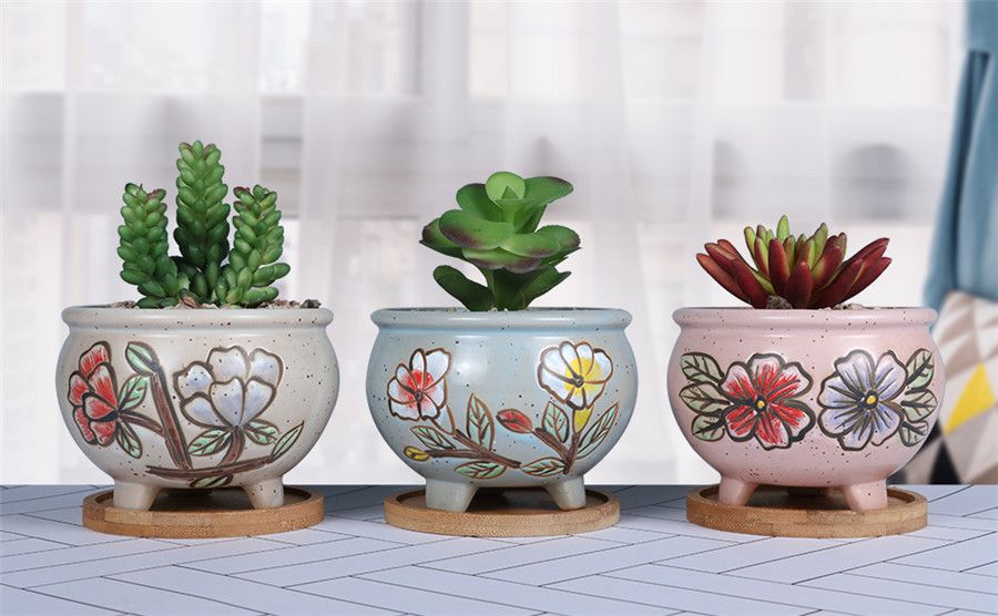 Three ceramic painted succulent pots put on the desktop in one line